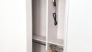 Ein Schrank mit Regalen, einer Kleiderstange und einer Steckleiste.