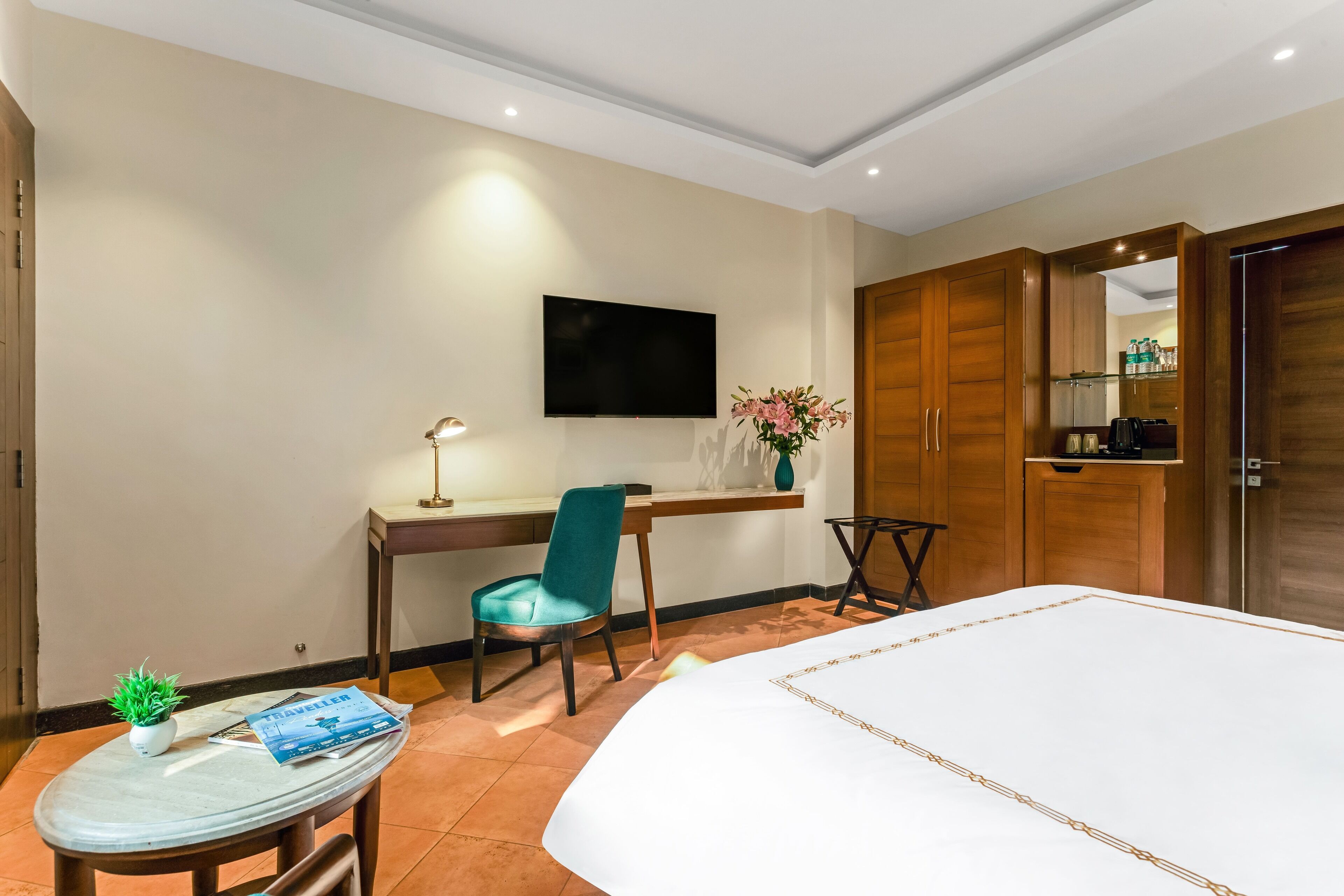 Une chambre d’hôtel comprenant un lit, un bureau avec une chaise, un téléviseur fixé au mur et une armoire.