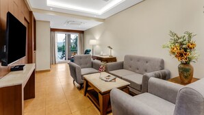 A modern living room with a flat-screen TV, grey sofas, a coffee table, and a vase of flowers. - Masaka Suites A Unit Of Arbat Hospitality LLP (Betalbatim)