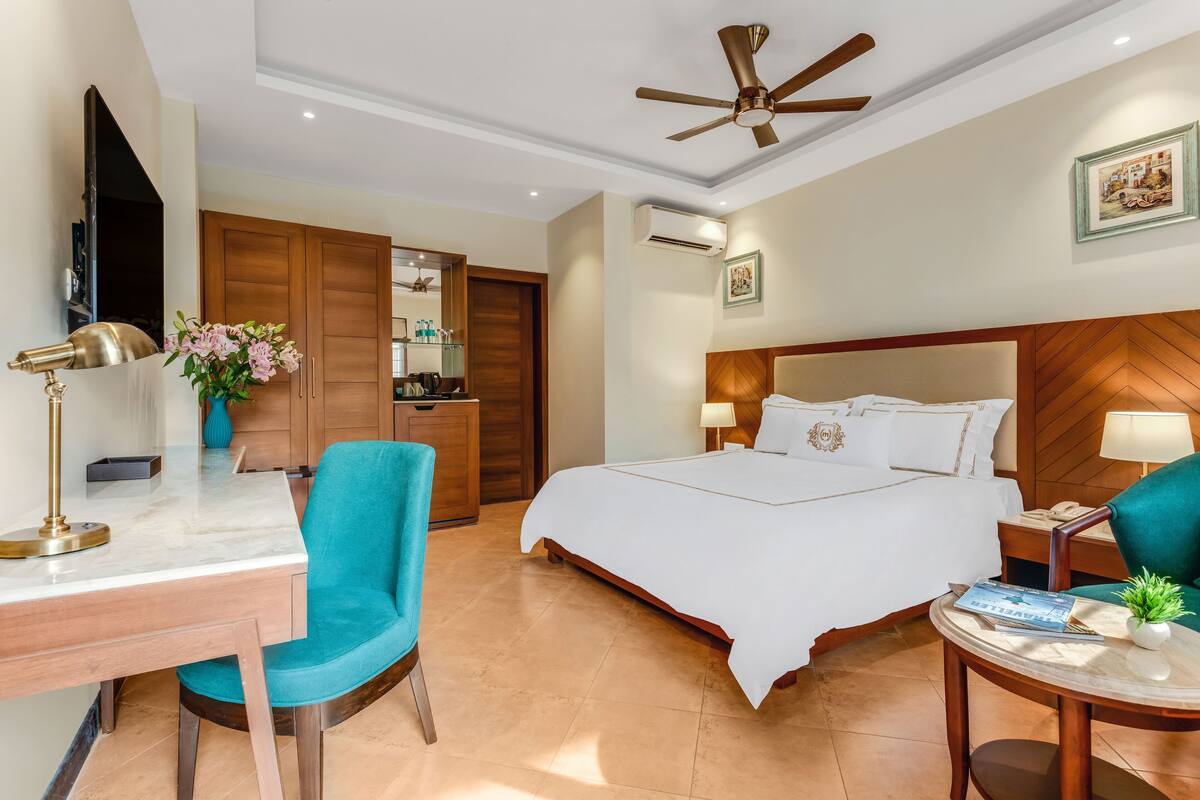 A hotel room with a bed, desk, chair, and a ceiling fan.