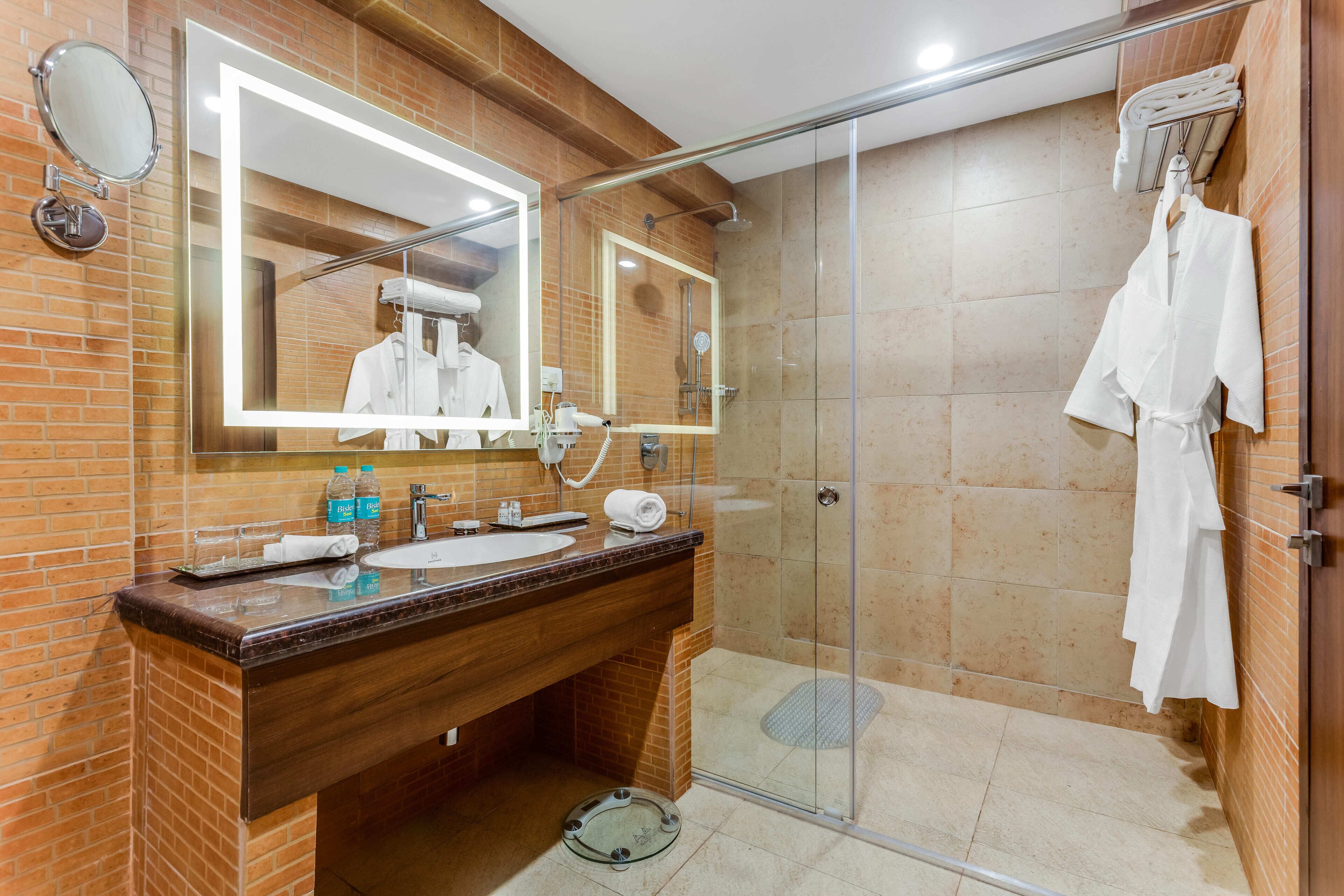 A modern bathroom with a glass-enclosed shower, a wooden vanity with a sink, and a large mirror.