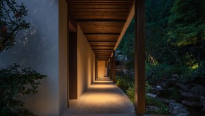 A corridor with wooden beams, a concrete floor, and a view of a natural landscape with rocks and greenery. - Xishan Cloister (Chengdu)