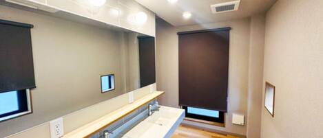 Un baño moderno con un lavamanos alargado, espejos e iluminación empotrada.