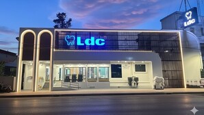 Un bâtiment moderne, reconnaissable à son grand panneau « Ldc », à ses larges fenêtres et à son entrée sécurisée par un portail.