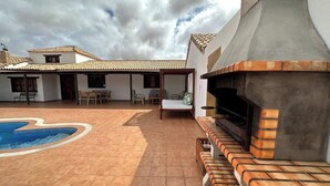 Un patio con piscina, mobiliario exterior y zona de barbacoa.