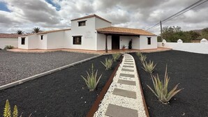 Un edificio con techo de tejas y fachada blanca. Un sendero conduce a la entrada.