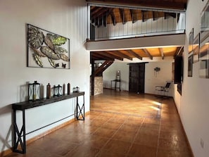 A spacious interior with a high ceiling, a staircase leading to an upper level, and a long console table with decorative items. - Villa with pool in the centre of Fuerteventura (Antigua)