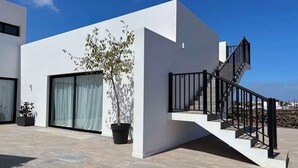 Edifici modern amb escala, grans finestres i plantes en testos.