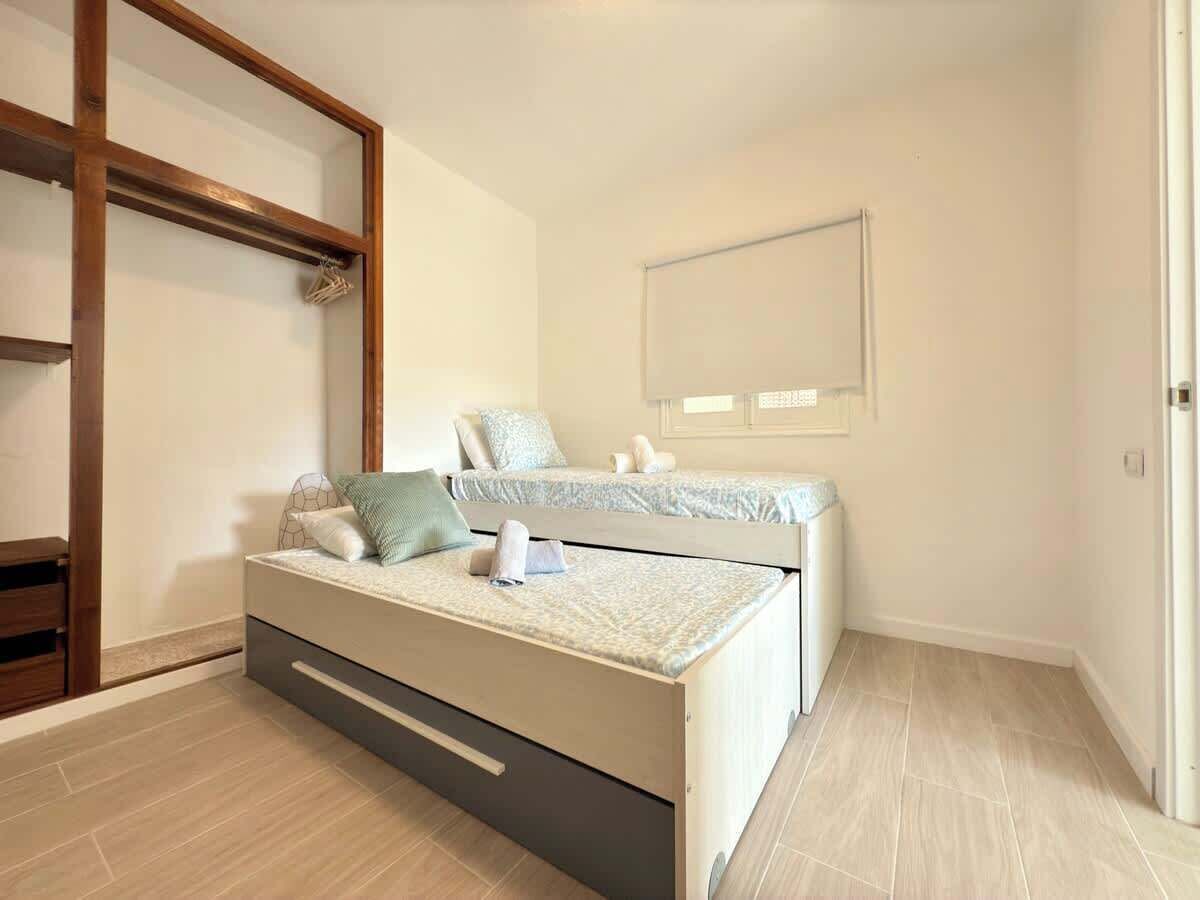A bedroom with a bed, a wooden wardrobe, and a window.