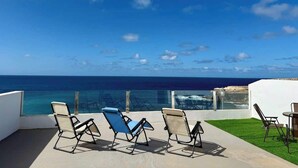 A terrace with a view of the ocean, featuring several lounge chairs and a small table. - House on the beach  WIFI Ajuy Fuerteventura (Ajuy)