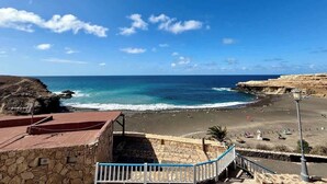A coastal view with a beach, rocky cliffs, and a clear sky. - House on the beach  WIFI Ajuy Fuerteventura (Ajuy)