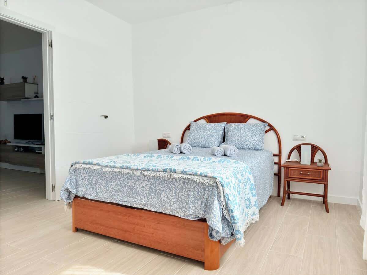 Une chambre à coucher avec un lit en bois, une table de chevet et une petite table avec une lampe.