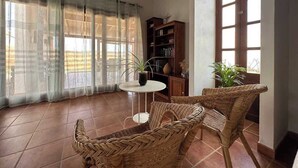 Una habitación con muebles de mimbre, una mesita y una estantería.