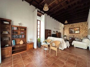 A spacious living room with a high ceiling, a fireplace, a bookshelf, and a dining area. - Villa with pool, views, barbeque and wifi (Pájara)
