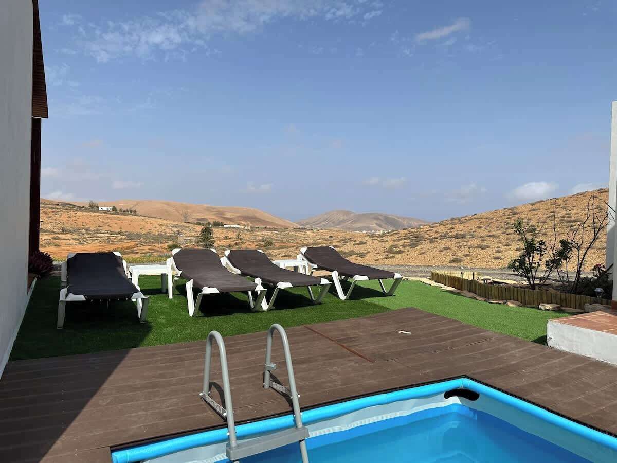 Ein Poolbereich mit Liegestühlen und Blick auf eine hügelige Landschaft.