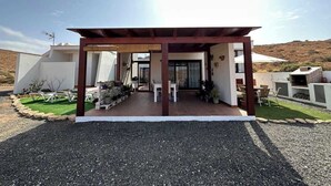 Una casa moderna con un porche cubierto, mobiliario de exterior y zona de barbacoa.