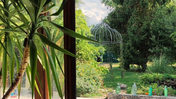Uitzicht vanuit een kamer met een houten deur naar een balkon met zwembad.
