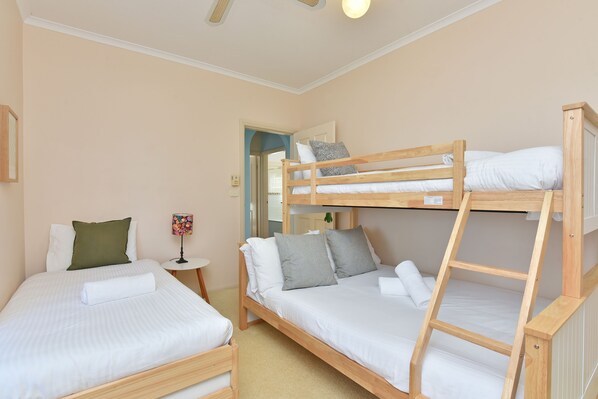A bunk bed room with two single beds, a small table, and a mirror.