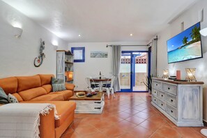 A living room with a sofa, coffee table, and a TV mounted on the wall. - CASA JUAN Unique private detached villa (Corralejo)