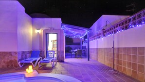 Ein Poolbereich mit Liegestühlen, einem Whirlpool und Lichterketten.