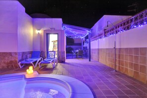 A pool area with lounge chairs, a hot tub, and string lights. - CASA JUAN Unique private detached villa (Corralejo)