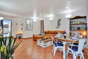 A living room with a sofa, a coffee table, and a dining area with chairs and a table set for a meal. - CASA JUAN Unique private detached villa (Corralejo)