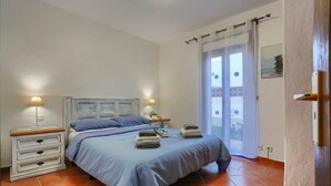 Ein Schlafzimmer mit Bett, Nachttischen und Blick durch ein Fenster.
