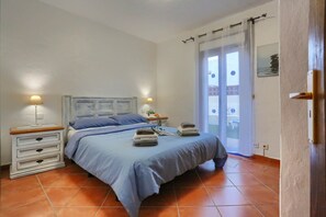 A bedroom with a bed, nightstands, and a view through a window. - CASA JUAN Unique private detached villa (Corralejo)