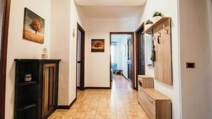 Un pasillo con suelo de baldosas, bancos de madera, un perchero y obras de arte colgadas en la pared.