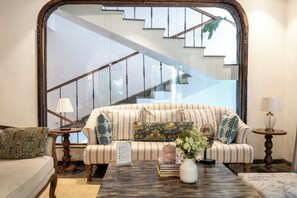 A living room with a striped sofa, a coffee table with books and a vase, and a staircase in the background. - Staymaster Stardust 3BHK Vagator  (Vagator)