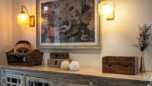 A room with a wooden cabinet, a framed painting, and two wall-mounted lamps. - Staymaster Stardust 3BHK Vagator  (Vagator)