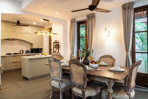 A dining area with a wooden table, wicker chairs, and a view of greenery outside. - Staymaster Stardust 3BHK Vagator  (Vagator)