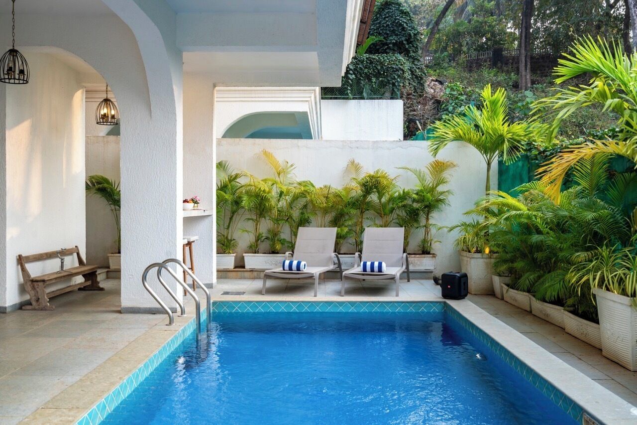 A swimming pool with lounge chairs and potted plants.