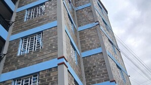 A multi-story building with a brick facade and blue horizontal bands. - Stacy's Cozy Bed and Breakfast in Nakuru, Kenya (Nakuru)