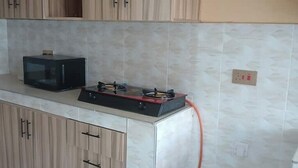 A kitchen with a microwave, gas stove, and cabinets. - Stacy's Cozy Bed and Breakfast in Nakuru, Kenya (Nakuru)