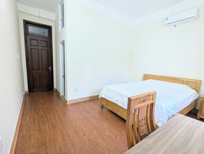Ein Zimmer mit Holztür, einem Bett mit Holz-Kopfteil und einer Klimaanlage an der Wand.