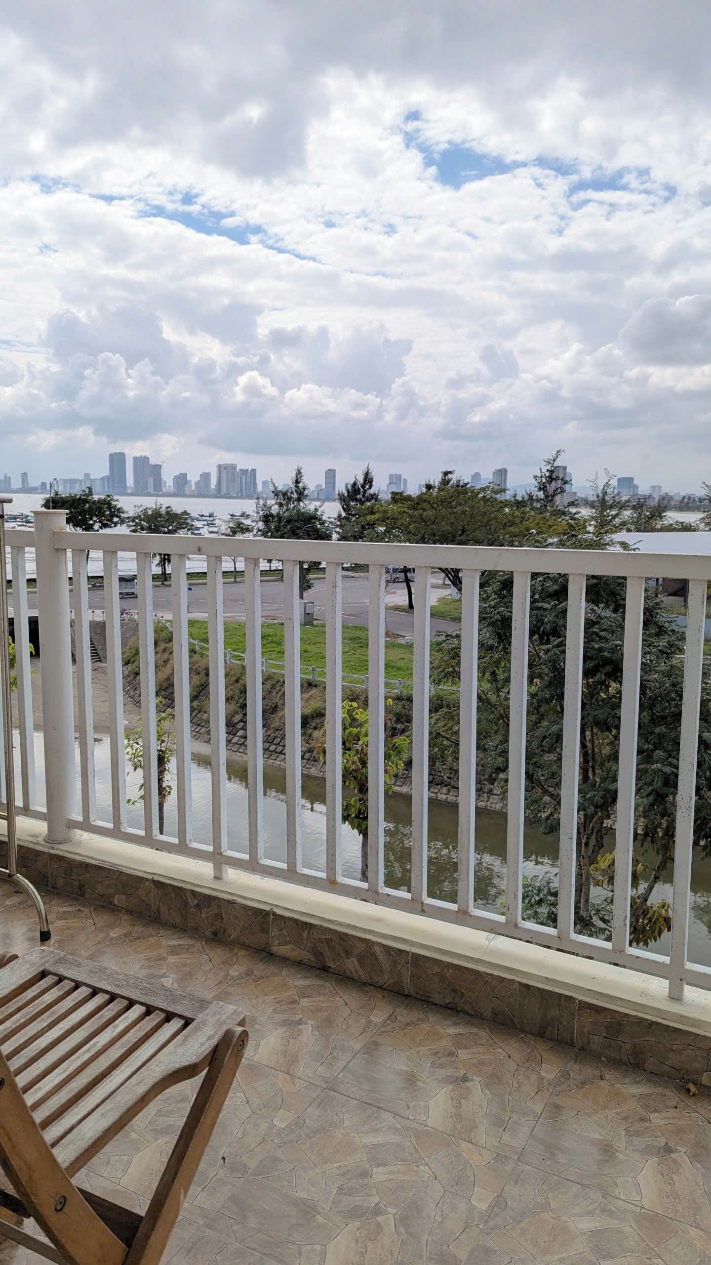 Een balkon met een witte railing, uitzicht op een rivier en een stadshorizon.