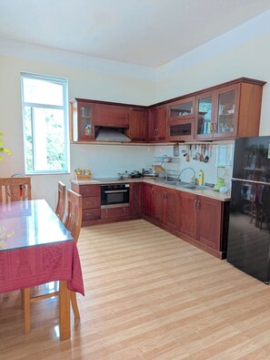 A kitchen with wooden cabinets, a stainless steel oven, and a black refrigerator. - AN Apartment (Son Tra)