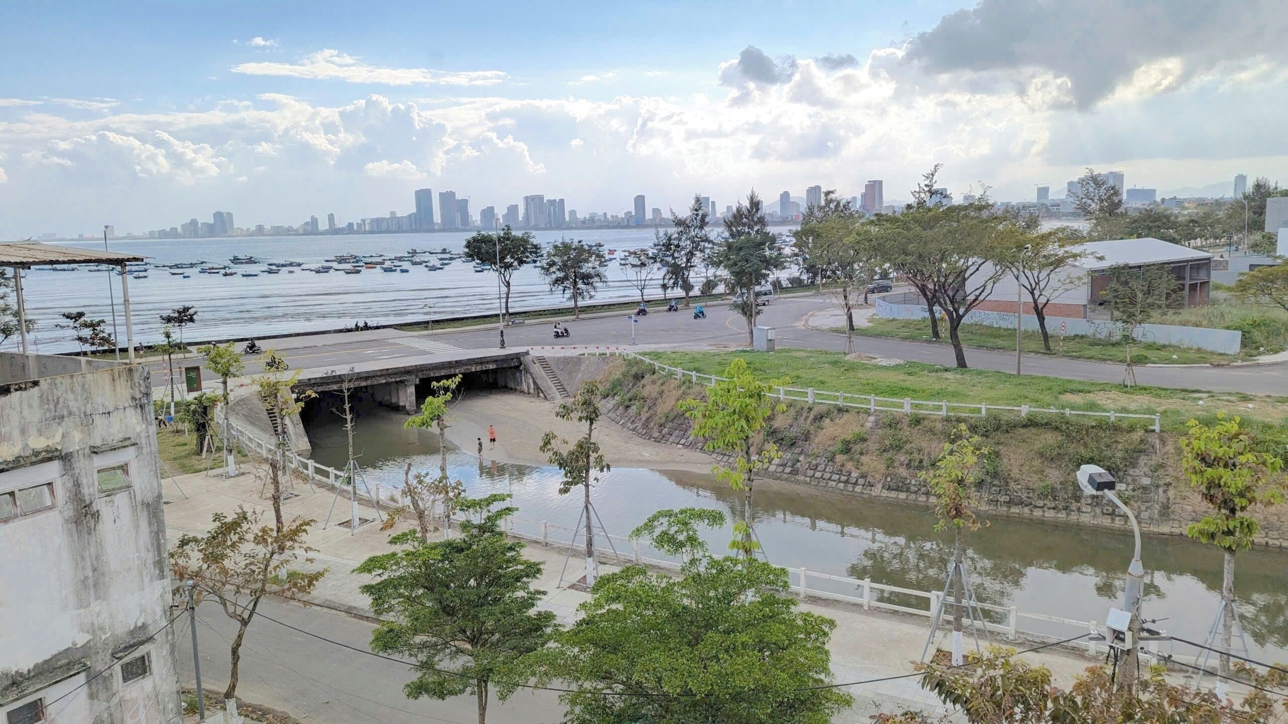 Una vista sul fiume con un ponte, barche e lo skyline di una città in lontananza.