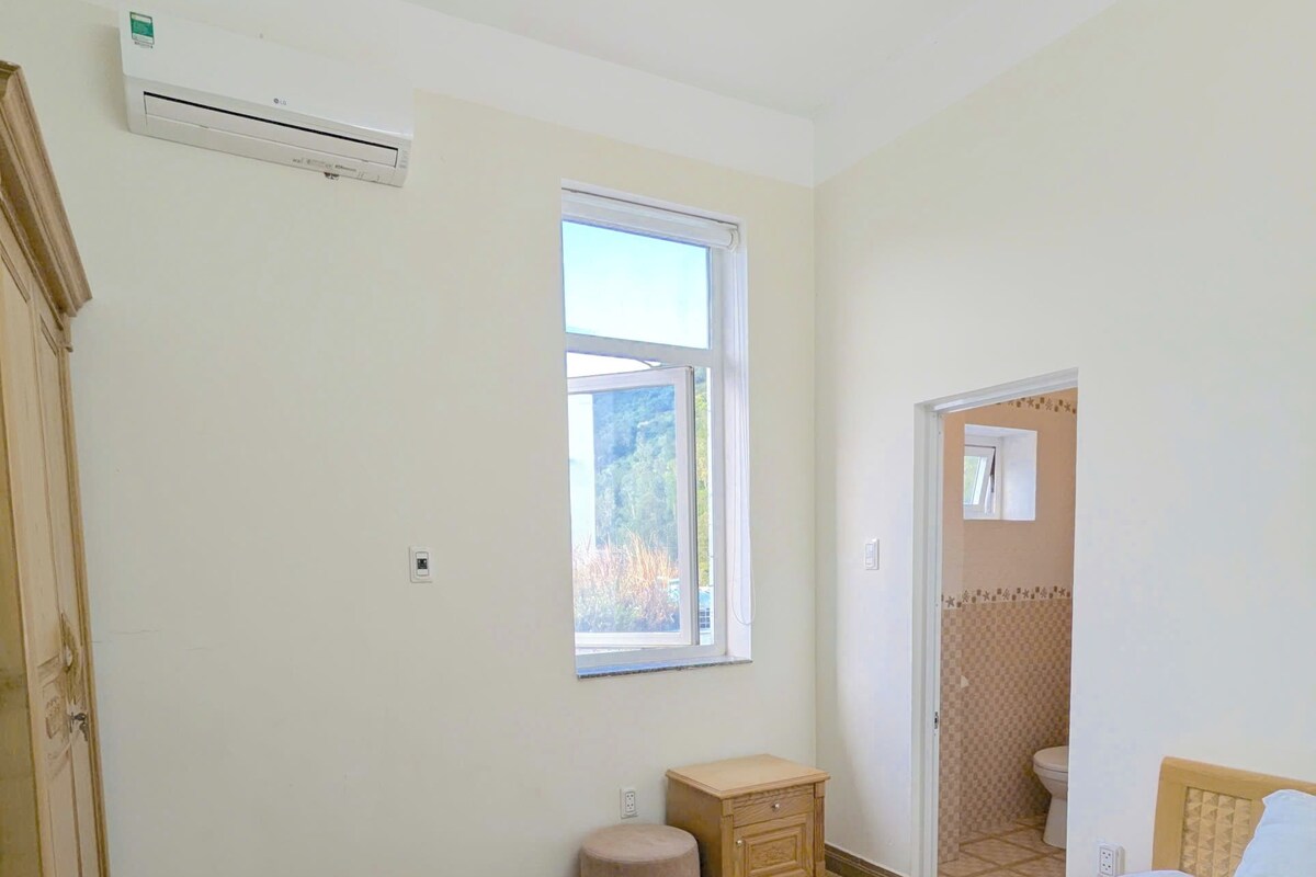 A bedroom with a bed, a small bedside table, a wardrobe, and a window.