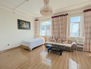 A room with a bed, a sofa, a glass coffee table, a chandelier, and a window with curtains. - AN Apartment (Son Tra)