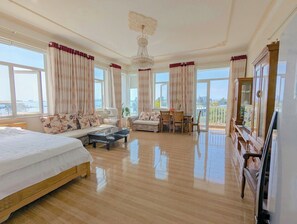 A spacious room with a large bed, a sofa, a dining table, and a TV. - AN Apartment (Son Tra)