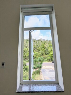 A window with a view of a parking area and a green landscape. - AN Apartment (Son Tra)