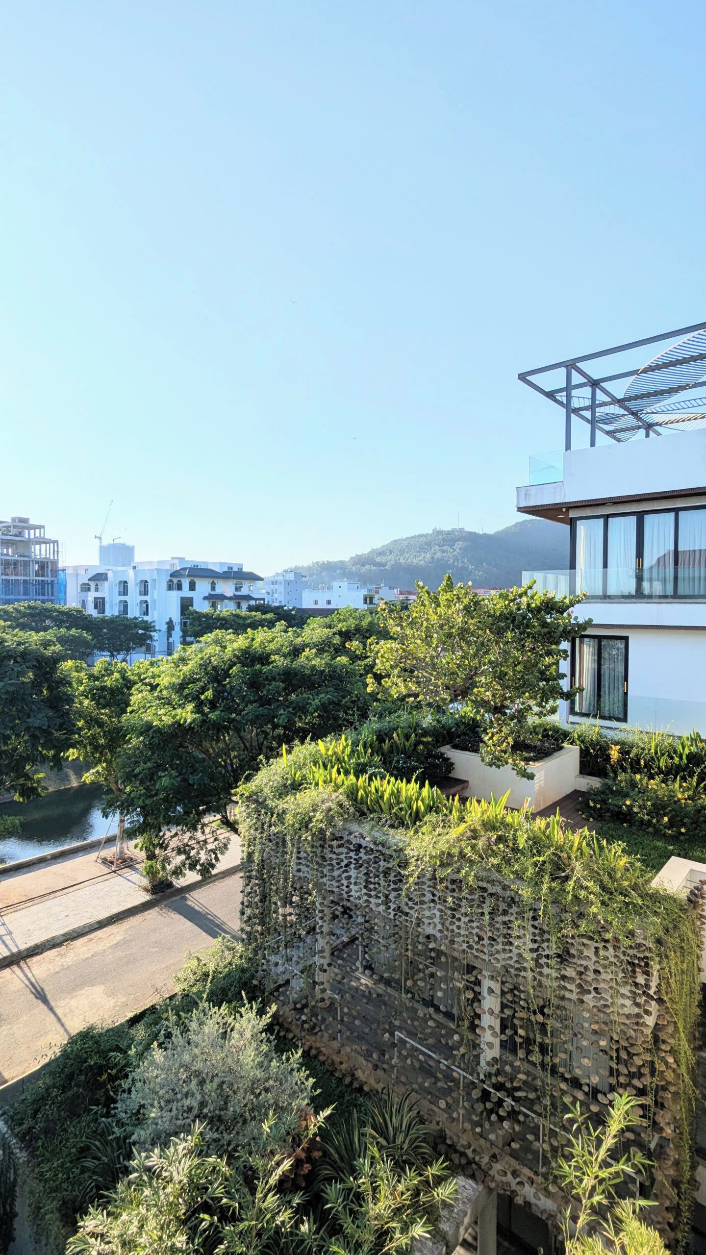 A residential area with modern buildings, a river, and a mountainous backdrop.