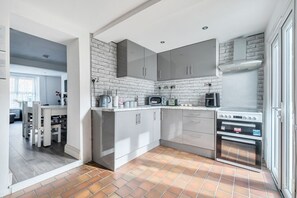 A modern kitchen with grey cabinets, a brick backsplash, and a built-in oven. - Valley views, hot tub and pool table — sleeps 8 in the Welsh hills (Cwmaman)