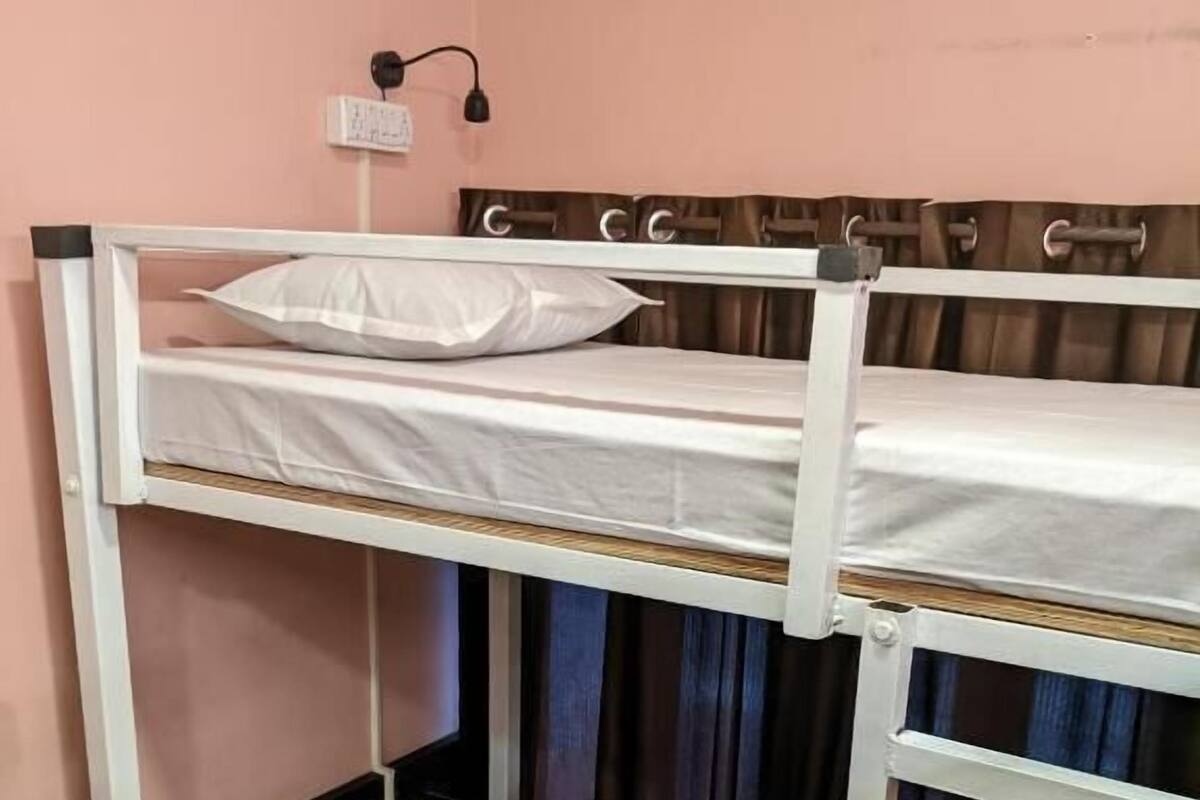 A bunk bed with white bedding and a wall-mounted light fixture.