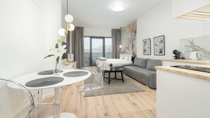 Una habitación moderna y bien iluminada con una mesa de comedor, sillas, un sofá, una cama y una zona de cocina.