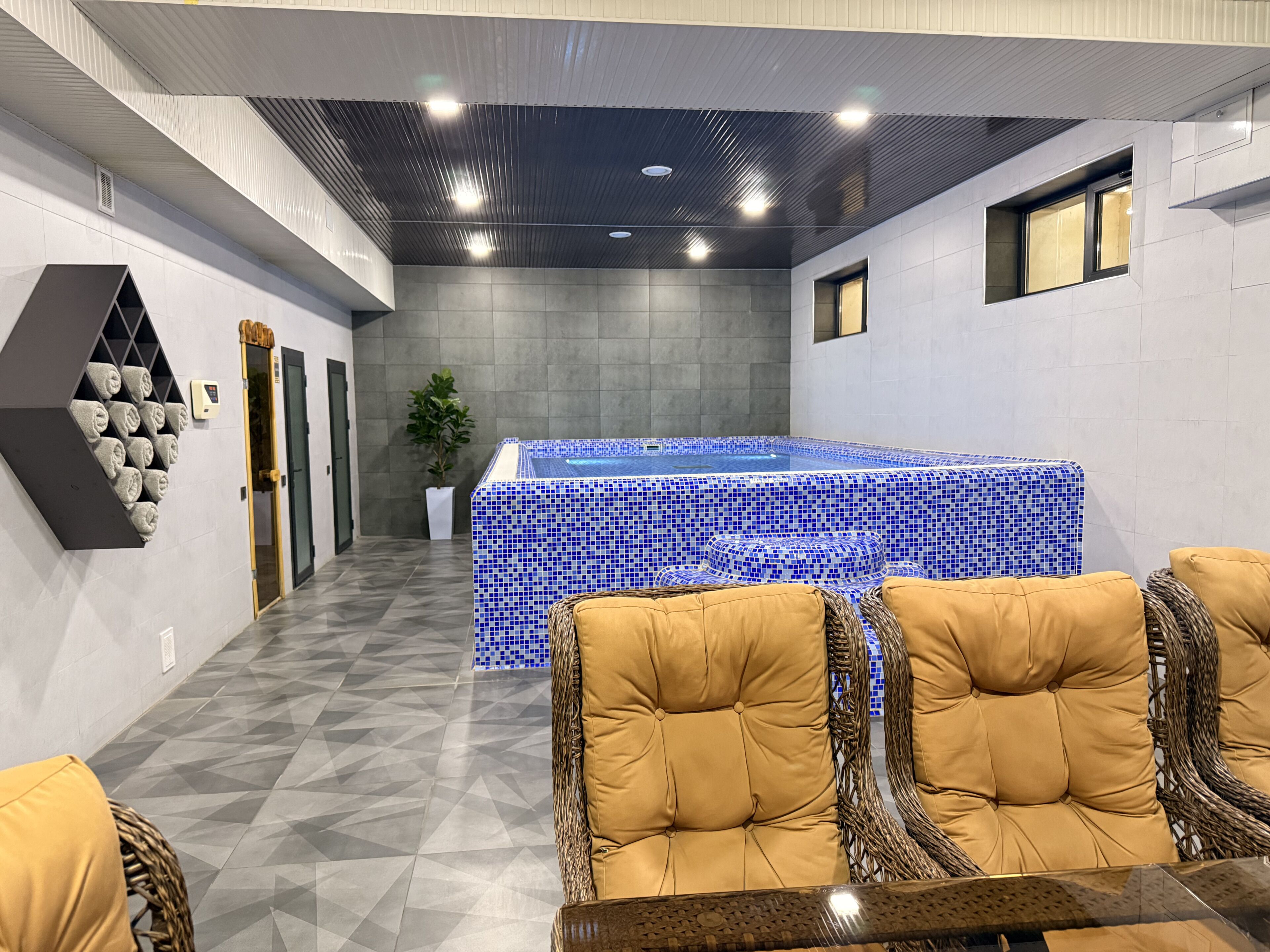 Un espace spa doté d’un bain à remous carrelé, de sièges confortables et d’un motif géométrique sur le sol.