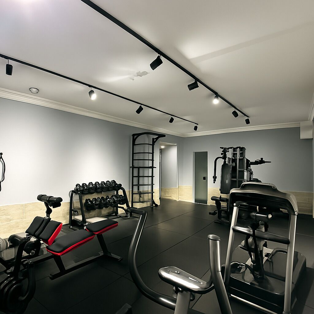 A gym with exercise equipment, a bench, dumbbells, and a wall-mounted rack.
