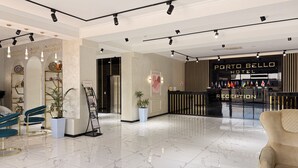 Een hotel lobby met een receptiebalie, een bar en een zithoek met stoelen en een bank.